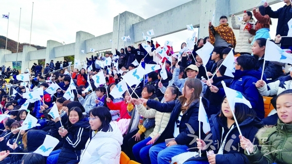 지난 29일 대회 개막식과 개막경기에 동원된 초등학생들이 경기를 응원하며 한반도기를 흔들고 있다.  유은숙 기자