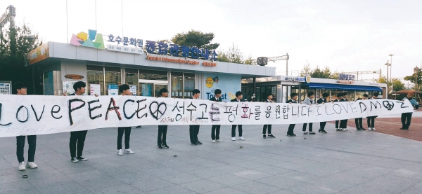 17일 춘천역 광장에서 평화를 염원하는 글씨를 쓴 후 한지띠를 들어올리는 성수고 학생들.        사진=한창환