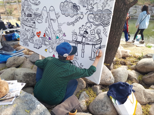 강촌 거리미술 축제에 참여해 천변에서 일러스트를 그리고 있는 한 예술가.