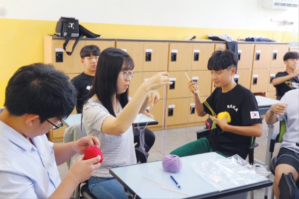 건축·토목과 1학년2반 박은미 담임선생님이 제자들에게 코 뜨는 방법을 설명하고 있다.