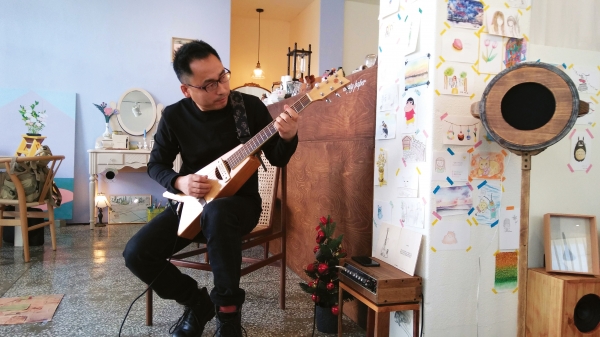 류재림 작가가 폐목재를 이용해 만든 기타를 연주하고 있다.